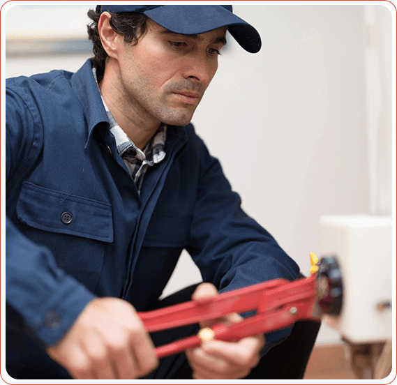 A plumber tightening a pipe with a wrench.